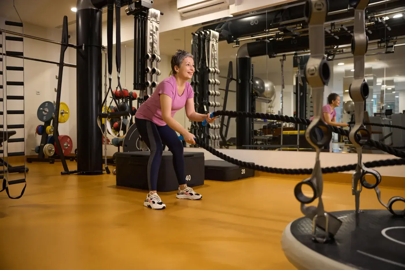 Mujer entrenando con cuerdas de batida en un gimnasio